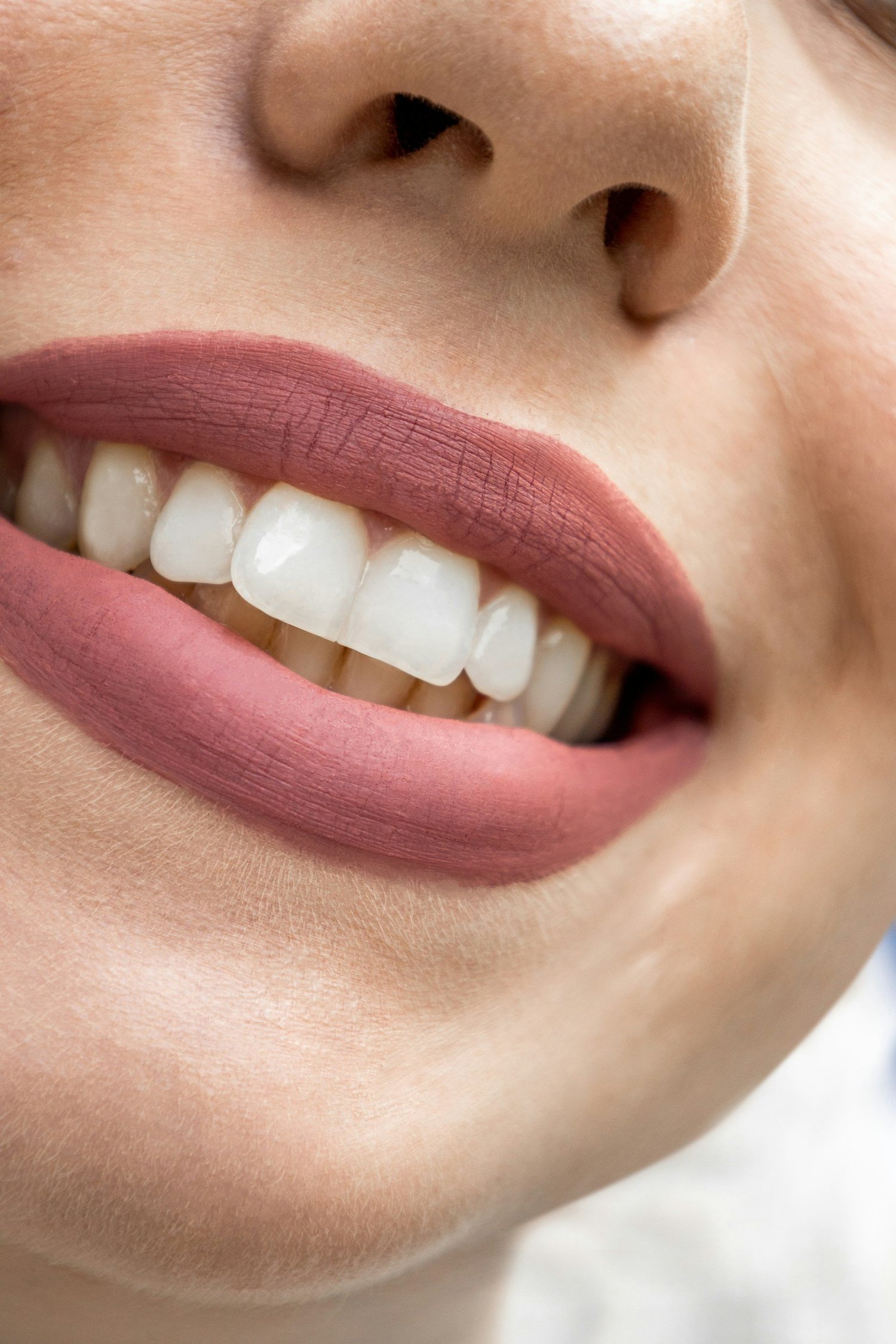 Primo piano di un sorriso con labbra dipinte di rosa e denti bianchi e dritti